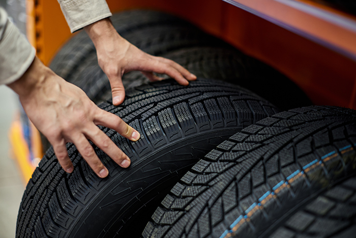 Person inspecting car tires on a rack.